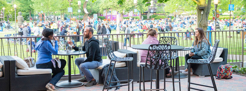 two couples eating outside at small tables on lawn bar patio